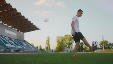 El-Jugador-De-Fútbol-Profesional-Está-Haciendo-Malabarismos-Con-Una-Pelota.-Socker-Un-Jugador-Con-Uniforme-De-Fútbol-Blanco-En-El-Estadio